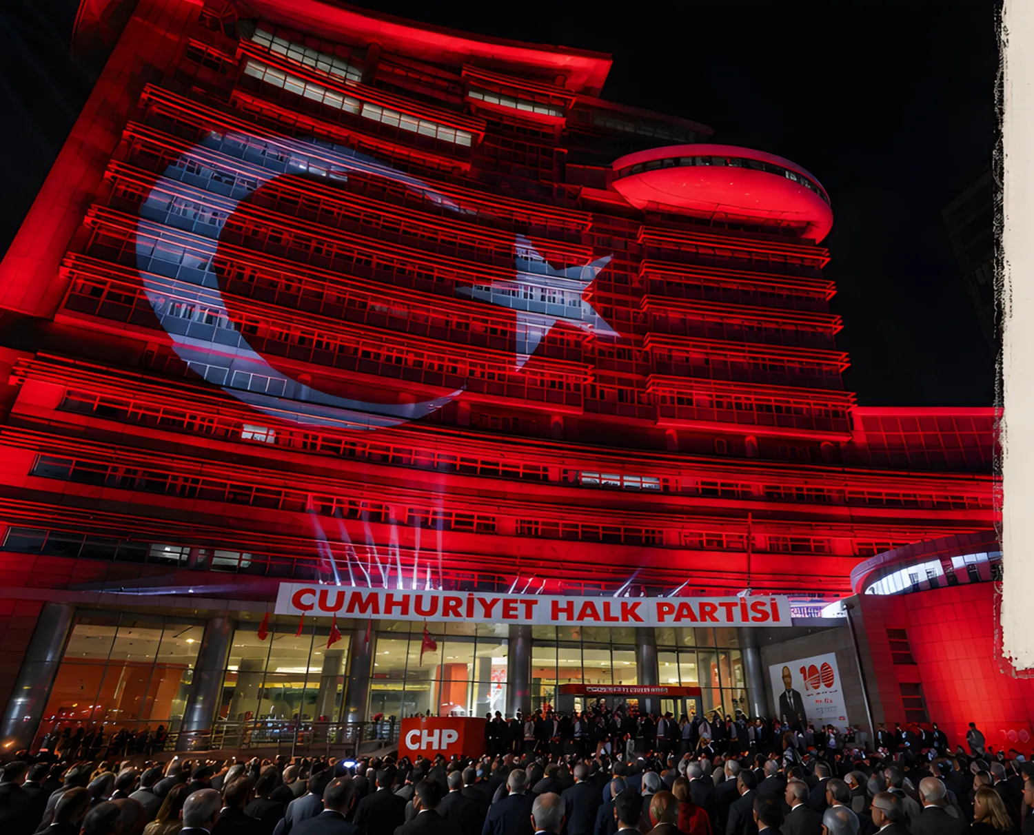 CHP headquarters in Ankara at night, its glass facade lit red with a projected Turkish flag, above a large crowd at the entrance.